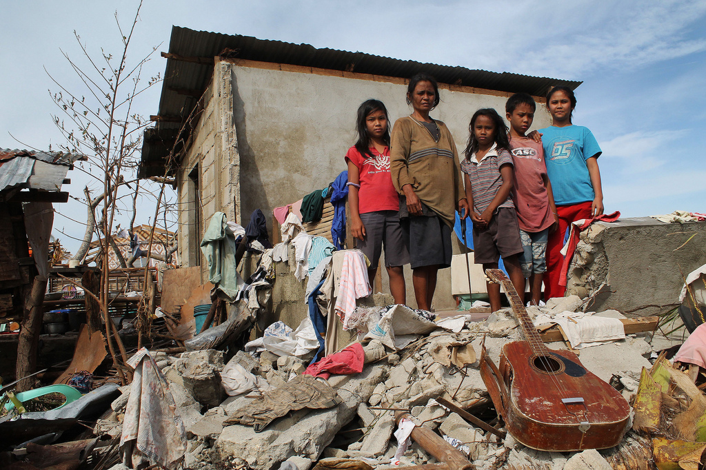 Family stands on rubble of their home in aftermath of storm.
