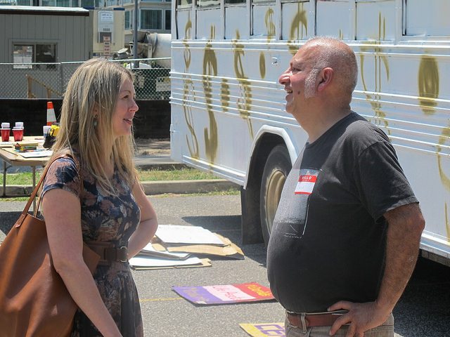 Photo of two artist in front of the "I Have a Home Here" bus.