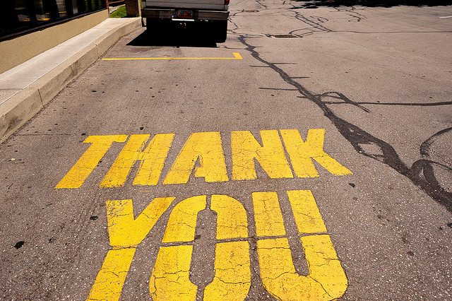 Image of the words "Thank You" on the pavement in bright yellow.