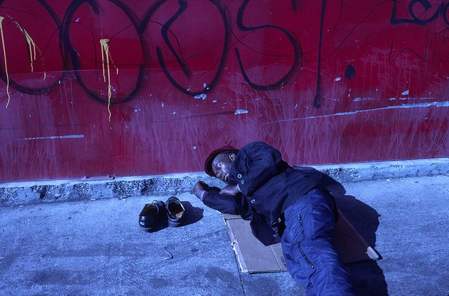 Image of a homeless man sleeping on the street.