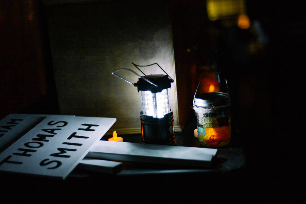 A photo of a lantern shining on a sign memorializing the name of someone who died while experiencing homelessness.