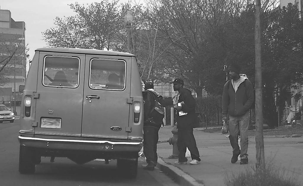 Photo of two men climbing in a van while another watches, in front of the service provider So Others Might Eat.