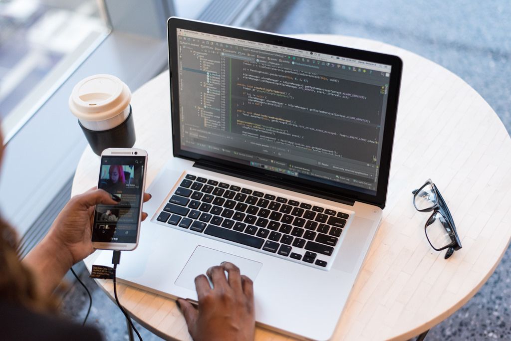 A person using a smart phone and a laptop