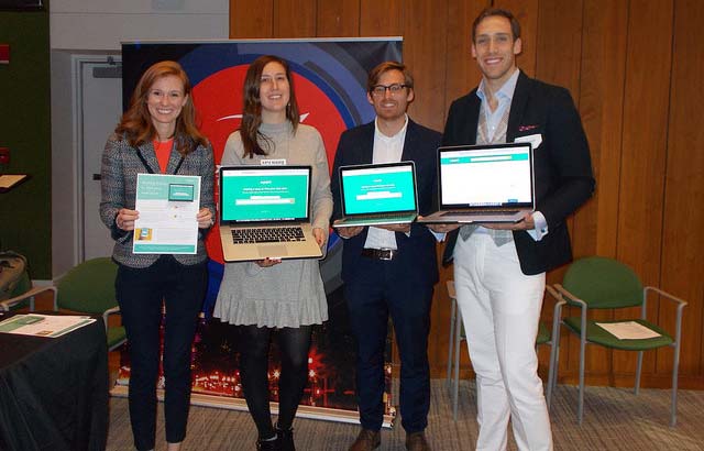 The team from Excella Consulting hold up laptops displaying the new website.