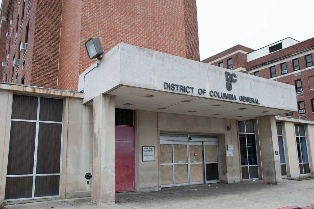 A photo of the entrance to DC General. The walls are dirty and there are boards over several windows.