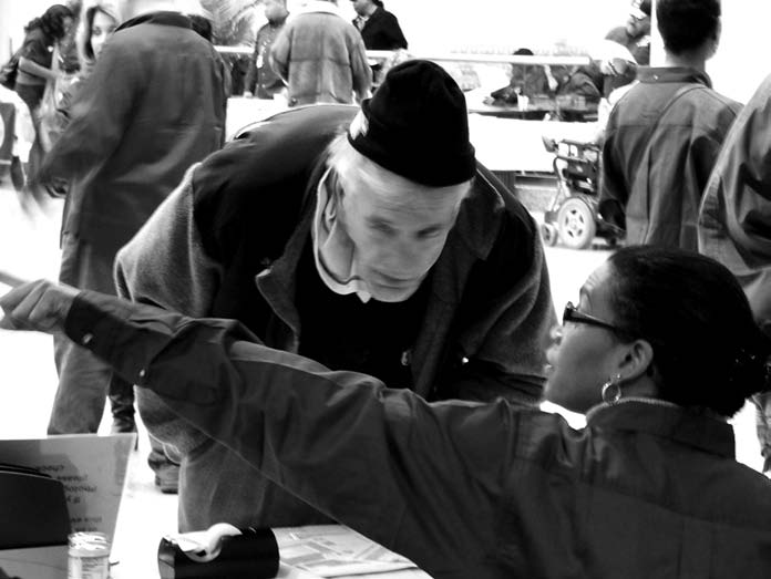 A veteran receives information from a worker at the Winterhaven Stand Down. Many tables like this one were set up on the first floor of the Medical Center to provide services and education to the homeless.