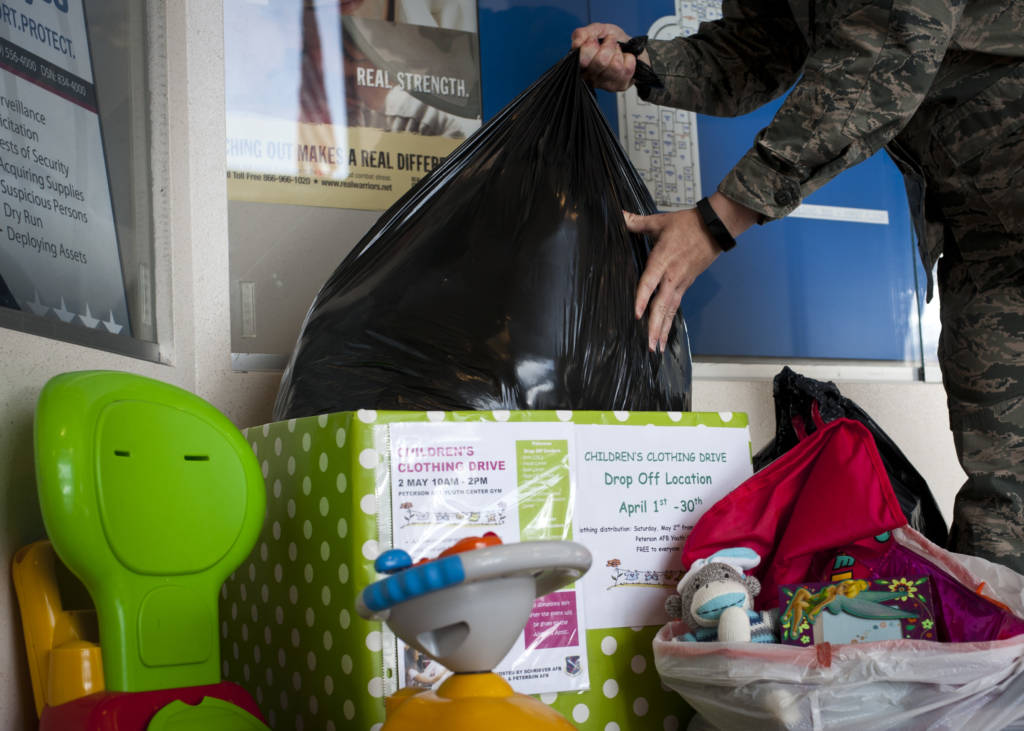 An Airman places a bag of gently used clothing a drop-box for the combined Peterson and Schriever AFBs children' s clothing drive at the 21st Mission Support Group headquarters building April 7. Clothing and toys for this event will be collected through the end of the month and will be distributed at the R.P. Lee Youth Center on Peterson AFB from 10 a.m. - 2 p.m. May 2