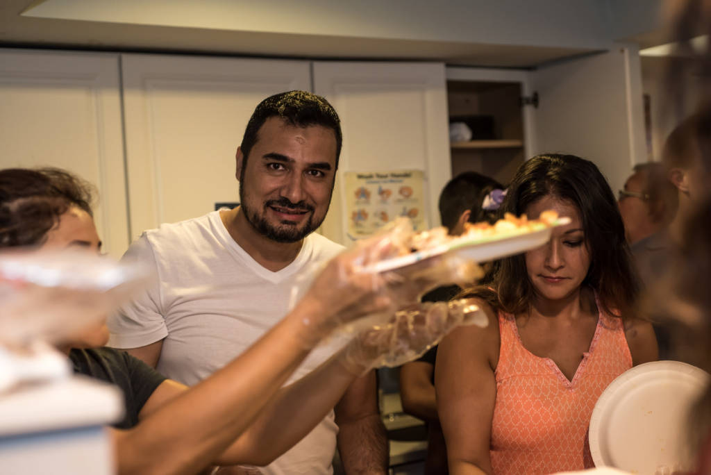 Photo of the restaurant owner, wearing a t-shirt, serving food alongside his the other volunteers.