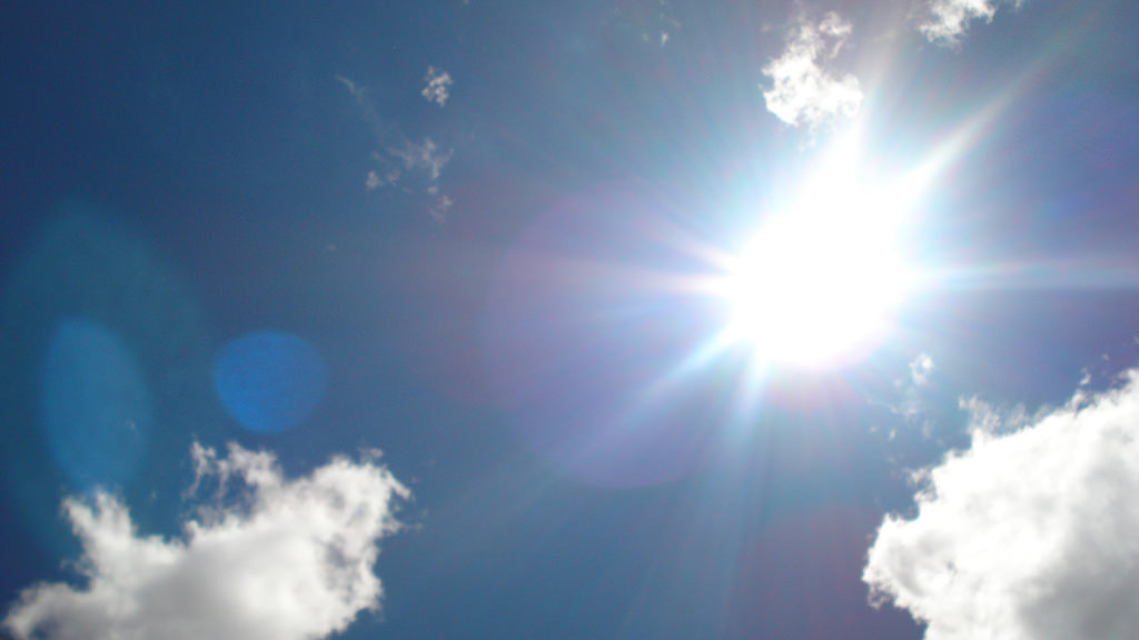 Picture of sun in the sky with few clouds
