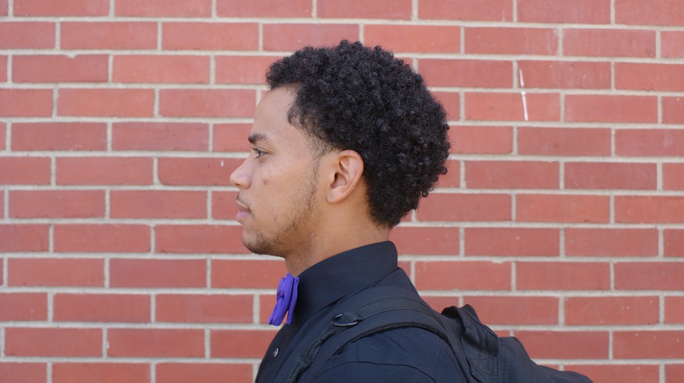 Side profile of a young man against a brick wall.