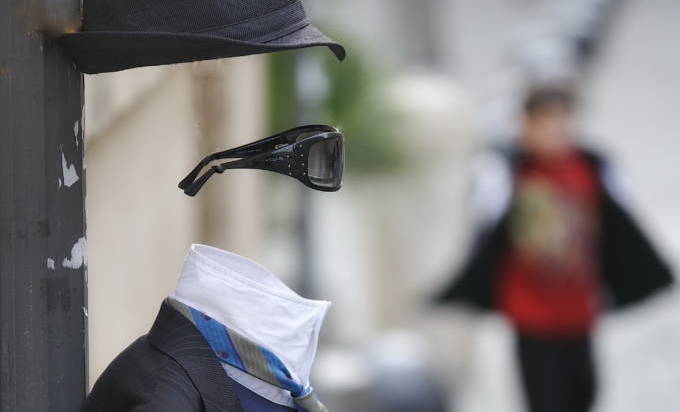 Photo illustration showing a man in a suit and sunglasses, but his body has been erased.