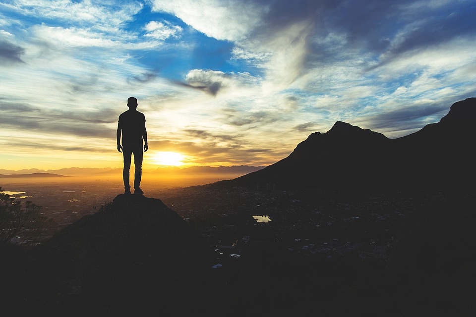 A photograph of a figure standing at a cliff.
