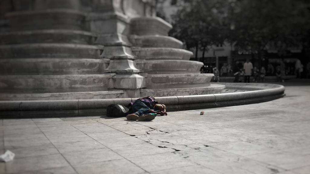 A person sleeping on the sidewalk.