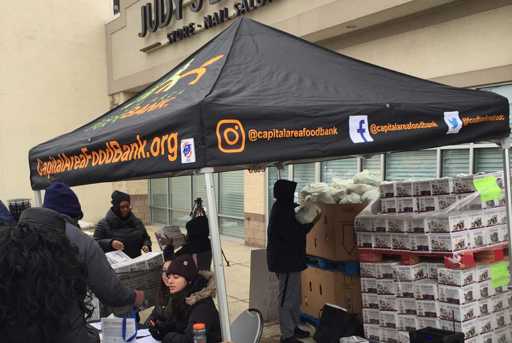 Photo of volunteers at a Capital Area Food Bank tent set up in front of Judy's Beauty Salon