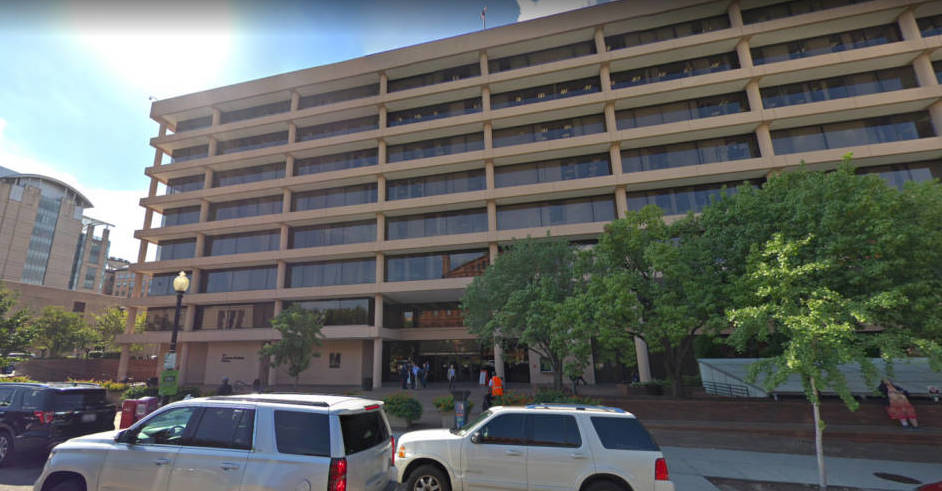 A photo of cars in front of a large office building with the WMATA "Metro" logo on the front.