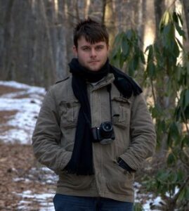 Photo of Ian standing in a wooded area.