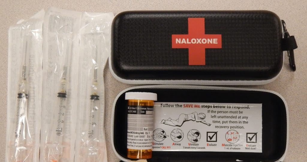 Photo showing a naloxone kit including a syringe, medication bottle, face mask, and instructions.
