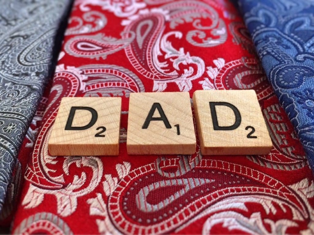 A photo showing a patterned red tie and scrabble letters spelling out "Dad."