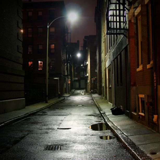 Dark city street with overhead lighting and puddles