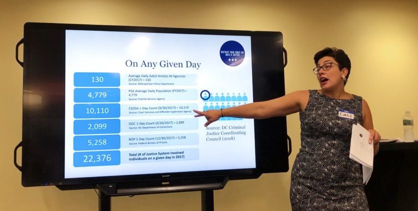 Photo of Emily Tatro pointing to a presentation on a monitor.