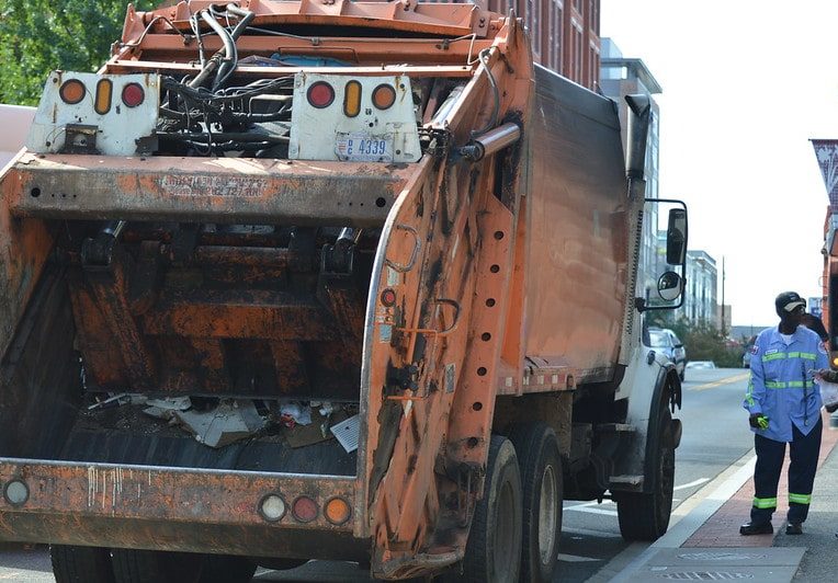 Image of a man standing by a garbage truck