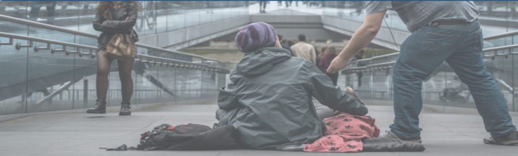 A homeless man is given an offering by a man walking by.