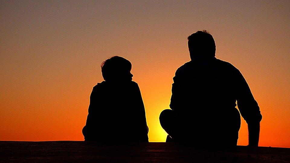 The silhouettes of a father and son sitting down.