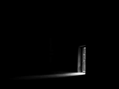 Light shines through a doorway in the darkness.