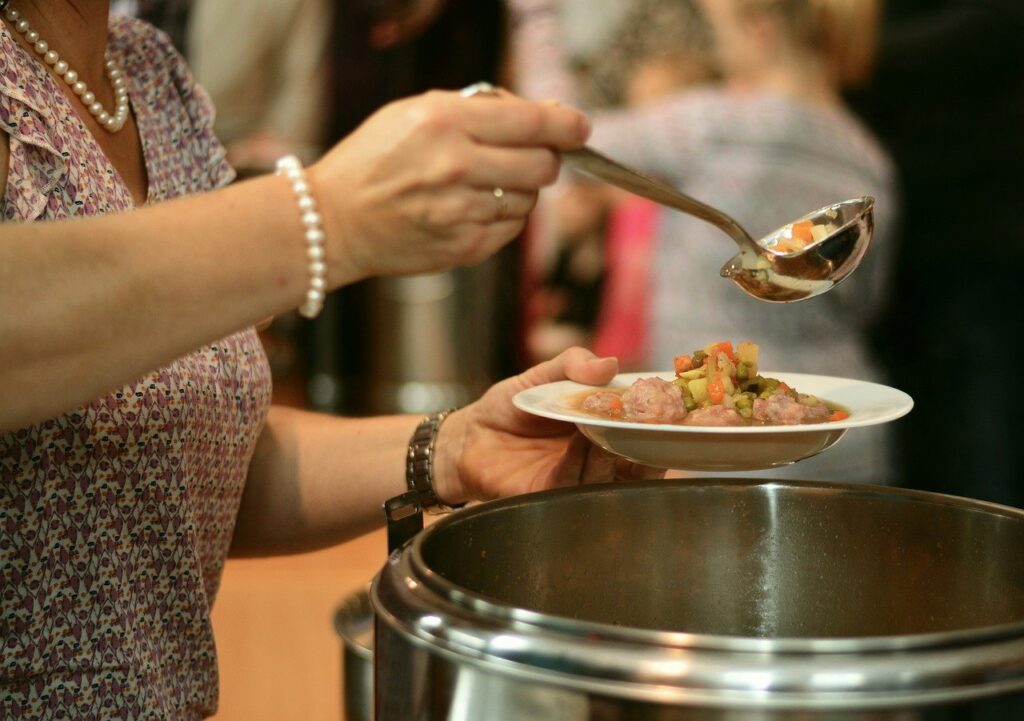 Someone puts soup into a bowl.