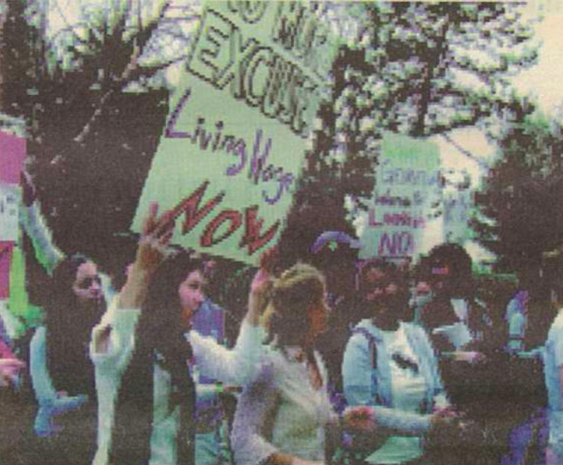 Students protesting, holding a sign demanding a living wage now.