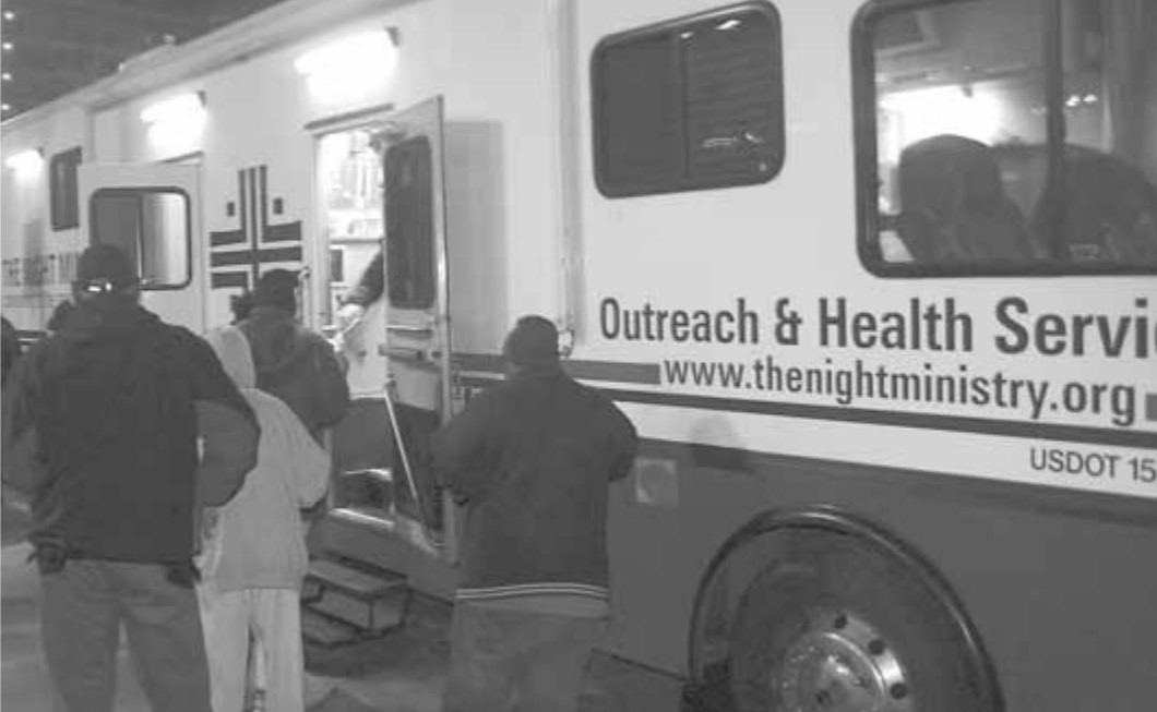 An image of men and women waiting in line for the Night Ministry Bus.