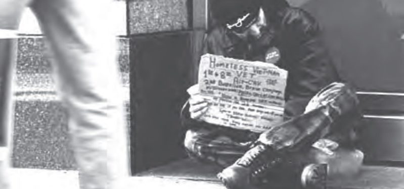 Photo of a homeless veteran holding a sign asking for assistance.