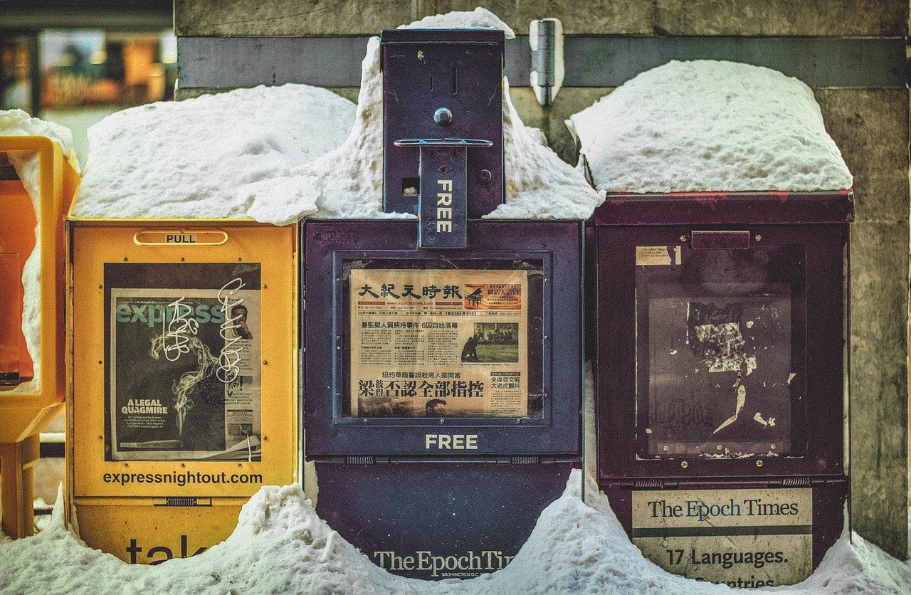 Photo of newspaper bins covered in snow.