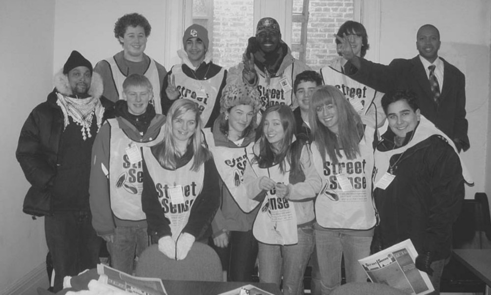 Photo of Street Sense Vendors posing with students from St. Andrews Episcopal School. The students are wearing Street Sense Vendor Vests.