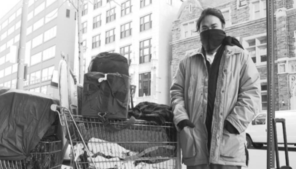 Carlo Laforteza stands next to two shopping carts full of his belongings.
