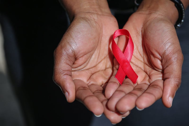 Photo of hands holding the red ribbon of HIV AIDS awareness