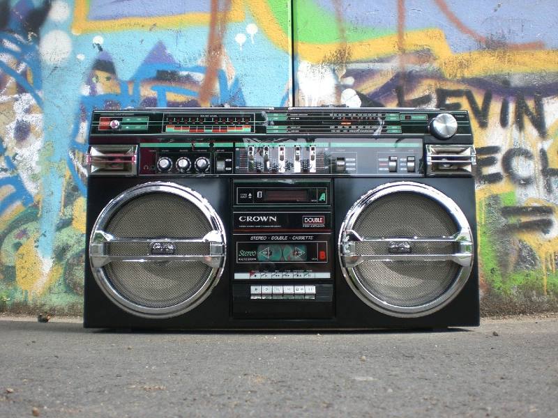 Photo of a boombox in front of a wall of graffiti.