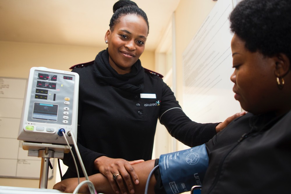 Photo of a nurse helping a patient with an arm cuff hooked up to a medical monitor.