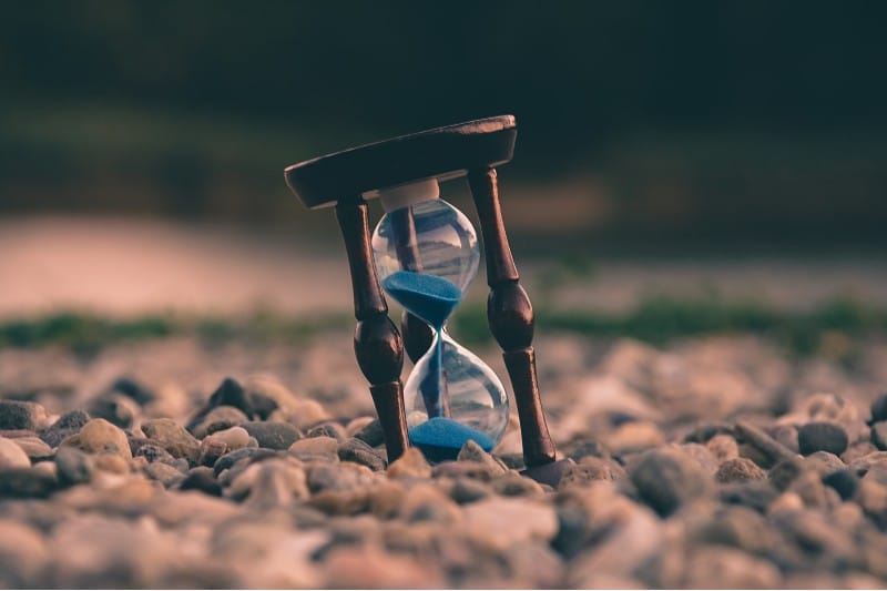 Photo of a hourglass partially buried in sand
