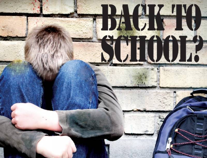 Photo of a student with his head down next to a backpack