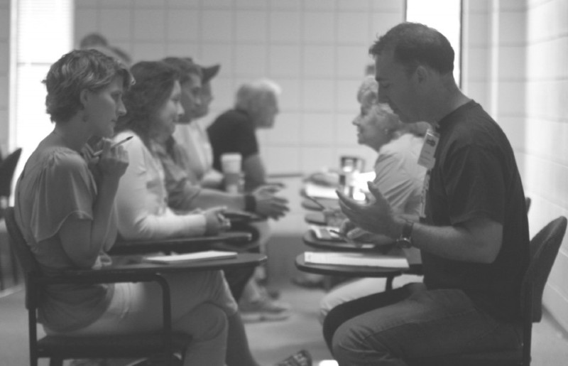 Photo of conference attendees facing each other in school desks