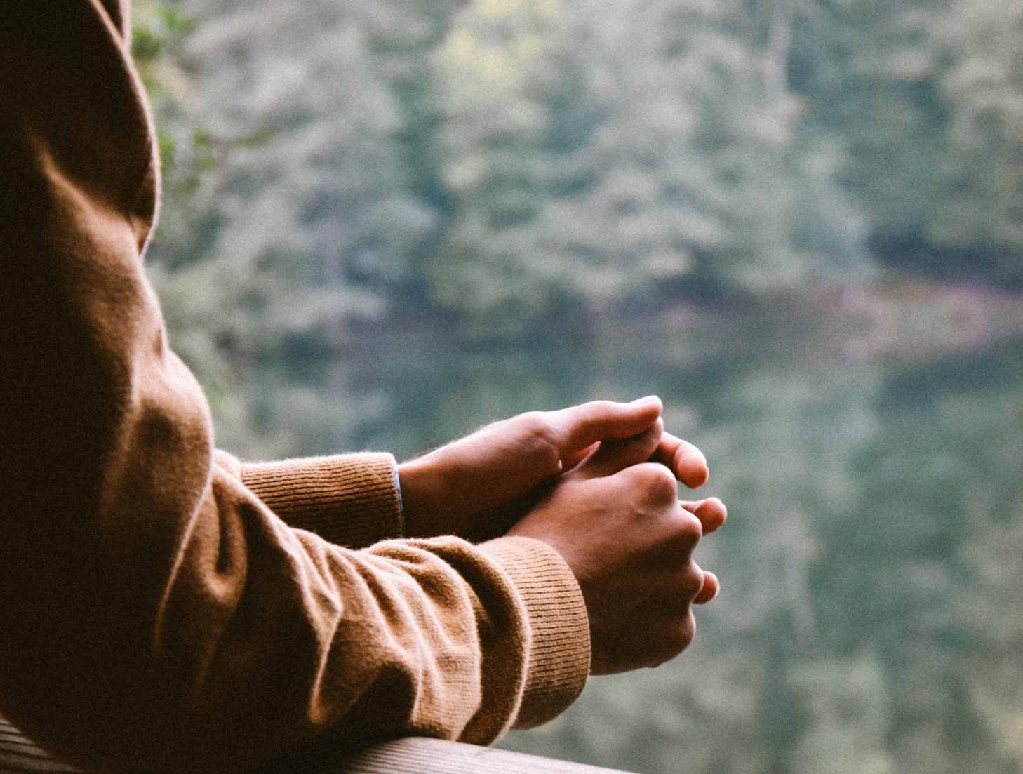 Photo of hands on a railing over a lake.