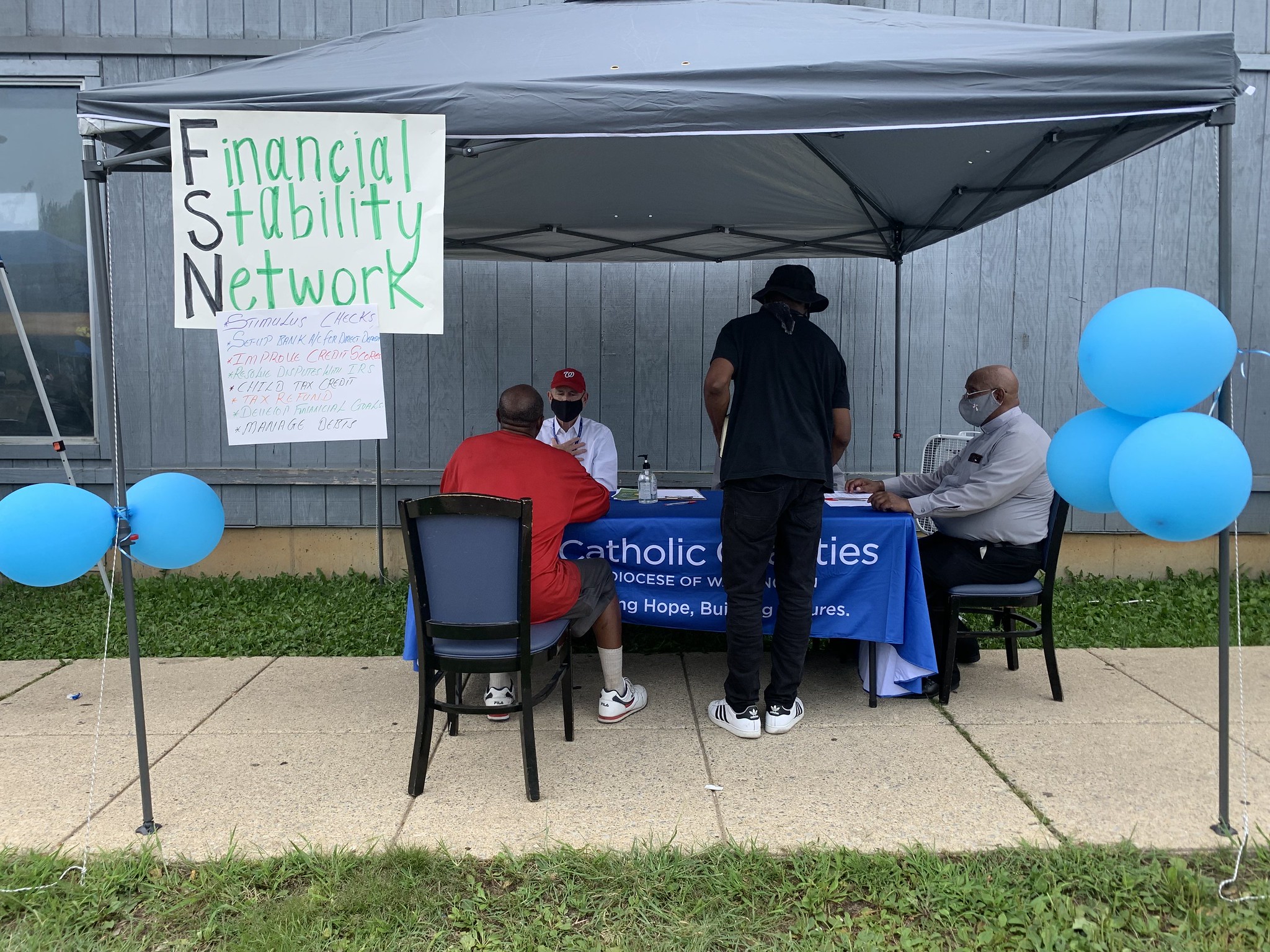Volunteers helping DC residents receive stimulus funding sit under a tent at a table