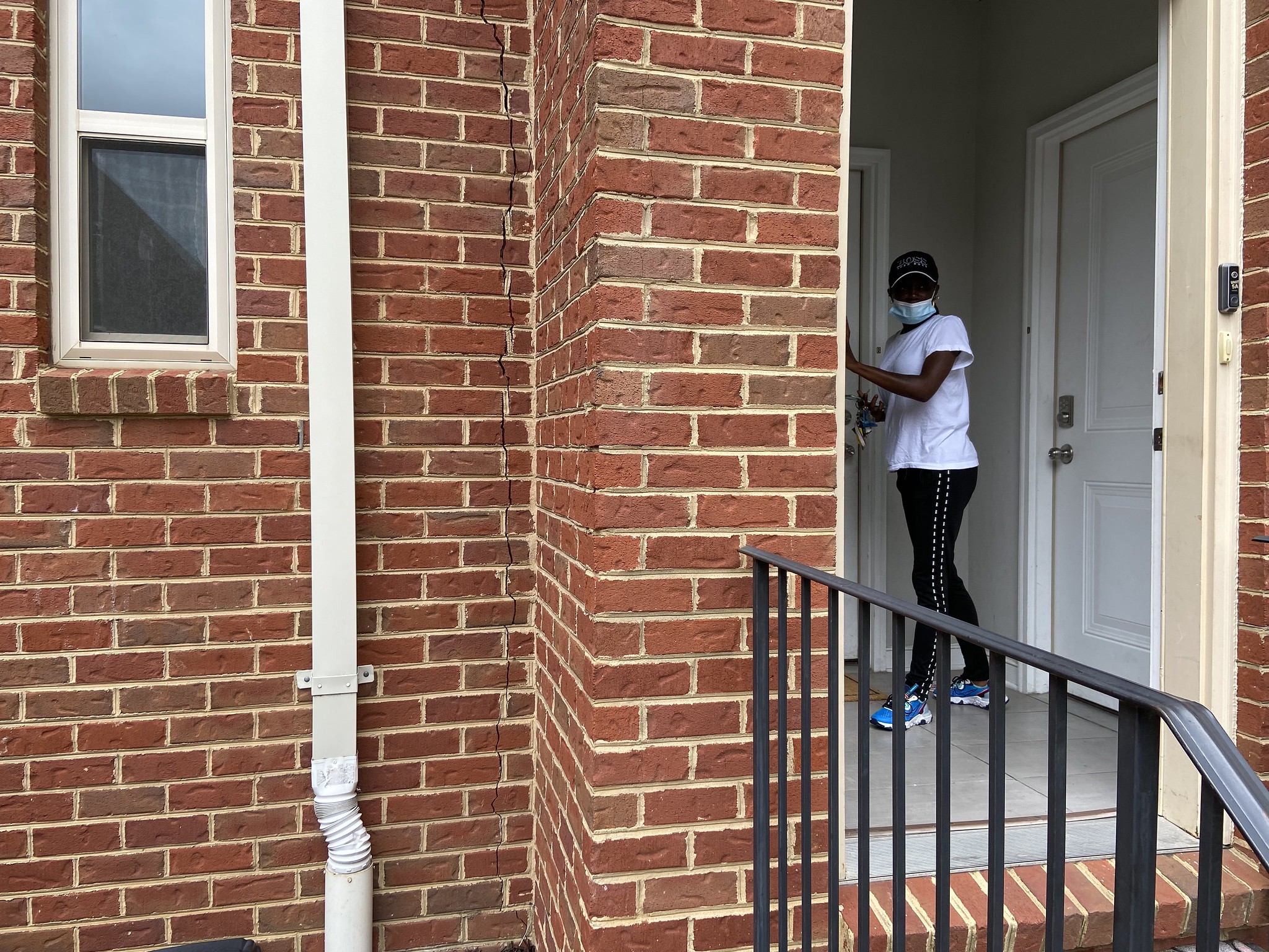 A woman stands in front of the door to her condo.