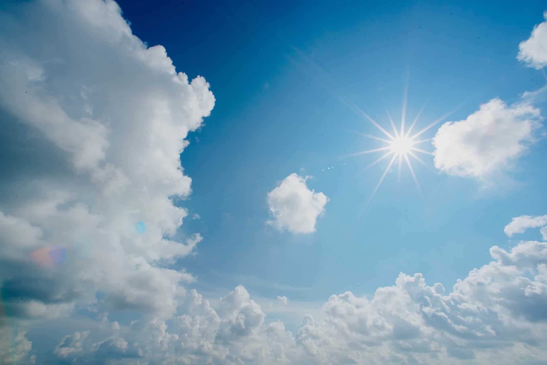 Photo of the sun shining against a blue sky.