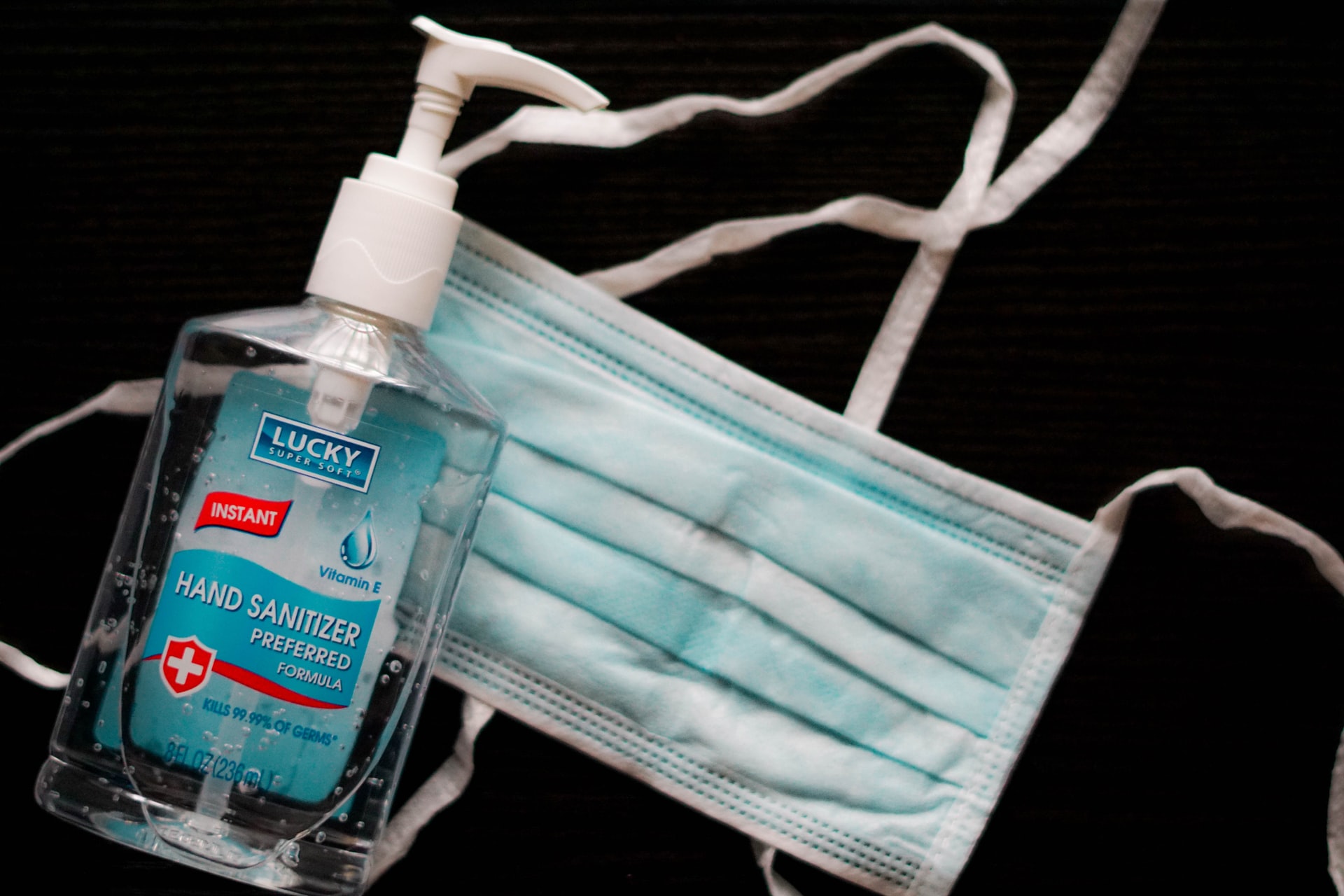 Photo of a blue mask with a bottle of handsanitizer in front of it.