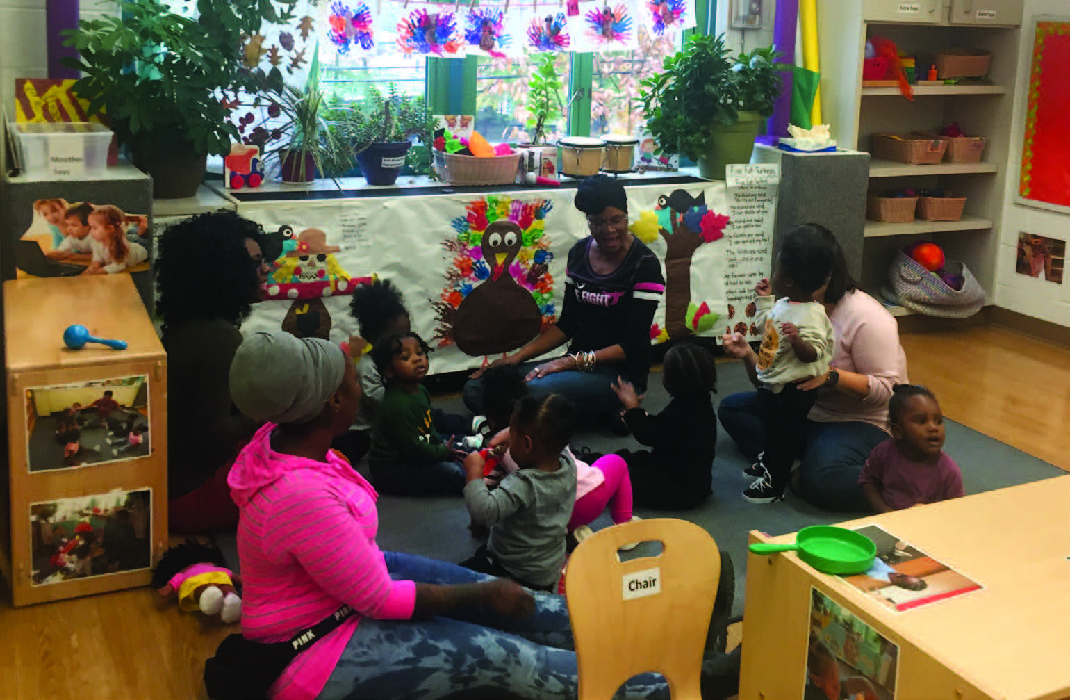 Photo of an adult and many children gathered in a circle on a mat.