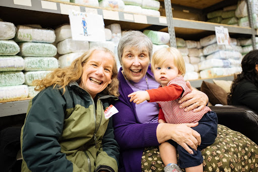Two women smile and hold a child.