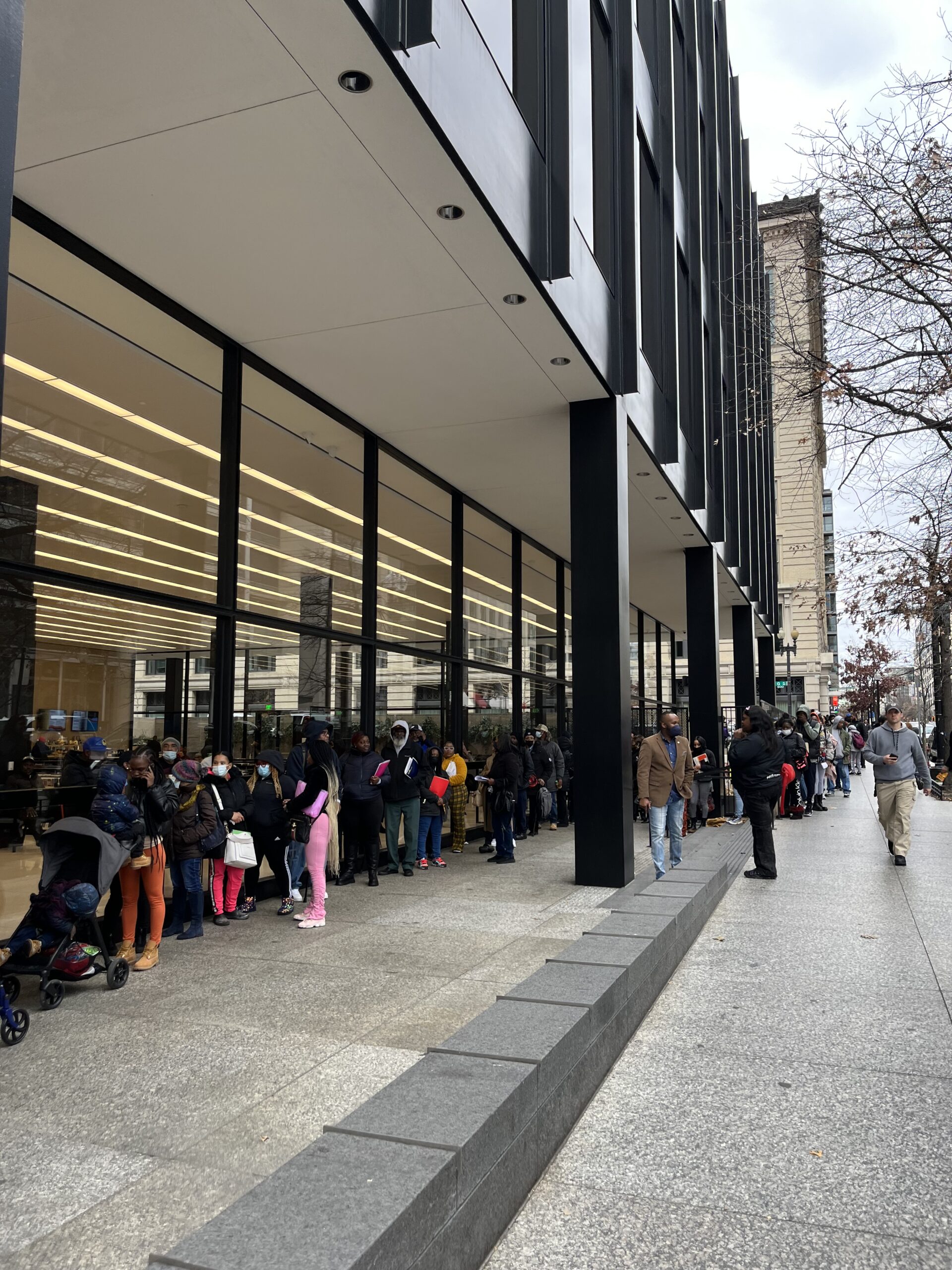 Dozens of people wait in a line outside