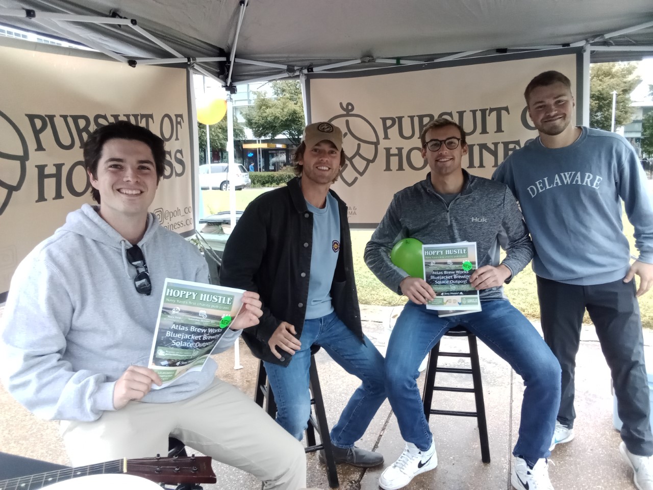 Four young men pose with posters.